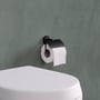 Montering af Cosmic toiletpapirholder i mat sort på en badeværelsesvæg ved siden af et toilet.
