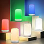 Opladelig LED bordlampe i hvid fremvist i forskellige farver, herunder rød, grøn, blå og hvid, på dekorative kuber.