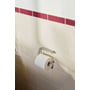 Knud Holscher toiletrulleholder fra d line i børstet rustfrit stål med en toiletpapirrulle monteret på en væg med lyse fliser.