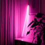 LEDlife Neon Tube LED i pink lyser op i et mørkt rum ved siden af en potteplante og en reol.