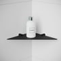 Enkel mat sort Cosmic Logic badeværelseshylde monteret i et hjørne med en hvid flaske på.