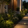 V-TAC dobbelt LED-spydspot lyser langs en havegang med begge spotlamper rettet mod beplantning og fliser.