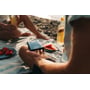 Nærbillede af en person, der holder en sort Verbatim Store ´n´ Go Slim SSD på en picnic ved stranden.