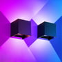 To LEDlife Cubic væglamper monteret ved siden af hinanden, der lyser op og ned i blå og pink nuancer.