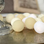 IrisLights lyskæde med 35 stk. Creamy White kugler i sandfarver, placeret på et dekorativt bakke.