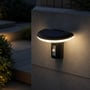 V-TAC LED-solcellehavelampen lyser varmt på en udendørsmur ved en trappe, med sensor synlig på fronten.