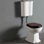 Lavabo Contea Retro Low toilet i hvidt med valnøddefarvet sæde står mod en grå væg og et mørkt gulv.
