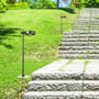V-TAC LED pullertlampe placeret ved siden af en stenbelagt trappe i en grøn have, oplyser stien med 3000K varmt lys.