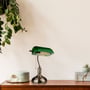 V-TAC skrivebordslampe med grøn glasskærm placeret på et træbord ved siden af planter.