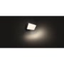 Philips Hue Welcome udendørs projektør lyser varmt mod en mørk baggrund og viser lysfeltets skær.
