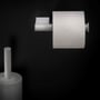 Cosmic toiletpapirholder uden låg i mat hvid, monteret på mørk væg med toiletpapir.