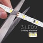 En saks klipper i V-TAC LED strippen ved markerede punkter for hver 3 LED'er, hvilket demonstrerer klippemuligheder for tilpasning.