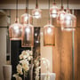 Tændte pendellamper med ravfarvede glasskærme viser V-TAC LED-kronepæren som lyskilde i en varm indretning.