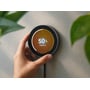 En hånd holder Homey Portal smart home-controller mod en væg, mens skærmen viser lysstyrke på 50 procent.