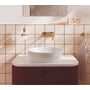 Grohe Lineare håndvaskarmatur i børstet warm sunrise monteret over en håndvask på en flisevæg.