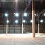 En stor tom lagerhal oplyst af adskillige V-TAC LED Highbay lamper monteret i loftet, der illustrerer effektiv rumbelysning.