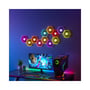 12 stk. LEDlife RGBIC Hexagon Infinity væglamper monteret på væggen som en kunstnerisk formation, oplyser et gaming setup.