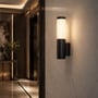 V-TAC LED-væglampe lyser på en væg i en entré, set sammen med rummets mørke interiør.
