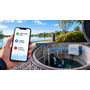 Watertec 4G PRO pumpestyring er monteret ved en vandtank, mens en mobil viser niveaualarmer og pumpestatus.