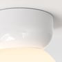 Tæt udsnit af den buede, hvide fatning og den lysende skærm på Astro Lighting Lyra Ceiling 180 loftlampen.