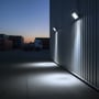 V-TAC LED-projektører er monteret på en lagerbygning og oplyser muren og belægningen ved skumring.