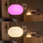 Philips Hue Flourish-pendel lyser pink og varmt hvidt i en stue og viser lampens farveskift.