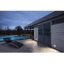 SLV BRICK indbygningsspot lyser op langs en husmur ved en terrasse og swimmingpool i skumringen.