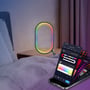 Detaljebillede af RGBIC lampe i ellipseform på et natbord, med fokus på de skiftende farver og den medfølgende smartphone med app.