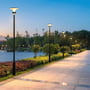 Flere V-TAC Lotus LED-solcellehavelamper lyser langs en bred sti i en park ved skumring.