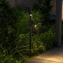 V-TAC dobbelt LED-spydspot står tændt i et havebed med lys fra begge spots rettet mod stien.