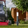 En mand klipper græs med en plæneklipper ved siden af en V-TAC pullertlampe i haven, der er tilsluttet strøm.