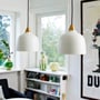 To Superliving Urban pendler i mat hvid med messing top, hængende i et vinduesparti med hylder og vaser i baggrunden.