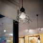 Industriel lampe med et sort metalgitter, der indeholder en lysende V-TAC LED pære i en butik.