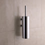 Vola T33 toiletbørsteholder i poleret krom, monteret på en lys, flisebelagt væg med skygge.