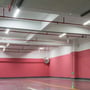 Indendørsbelysning i et parkeringshus med V-TAC LED-armaturer langs loftet og markante røde rørinstallationer.