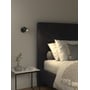 Astro Lighting Ascoli Single spot i mat sort er monteret ved siden af en seng og lyser ind over sengebordet.