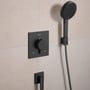 Hansgrohe Raindance Alive Select S brusesæt i børstet sort krom, med indbygningsarmatur, håndbruser på holder og tekstilbruserslange monteret på cremefarvet flisevæg.