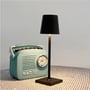 Sort LED mini bordlampe tændt på et bord ved siden af en vintage lyseblå radio dekoration.