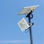 V-TAC 50W solpanel LED projektør monteret på en mast mod en klar blå himmel, viser dens udendørs anvendelse.