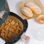 Nordic Quality airfryer bagepapir i brug med friturestegt kylling i airfryer-kurv og bagværk ved siden af.