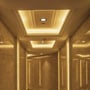 Varmt og indbydende lys fra flere V-TAC LED downlights i en korridor med marmorvægge og indbyggede lyspaneler.