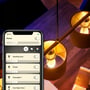 Philips Hue White E14 LED-kertepære lyser i pendler, mens Hue-appen på en telefon viser lysstyring.