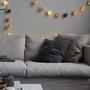IrisLights lyskæde med 35 LED-lys i grå, creme og lyserøde nuancer, vist hængende over en sofa.