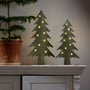 Star Trading Fabbe Deko træ i grøn med lys står på en kaminhylde sammen med et mindre juletræ.