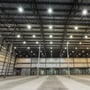 Indvendigt billede af et lager med stålbjælker og mange tændte V-TAC LED højby lamper i loftet.