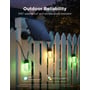 Govee Outdoor Solar String Lights lyser grønt og varmt hvidt på et hegn i regnvejr sammen med solpanelet.