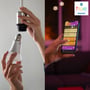 Philips Hue White E14 LED-kertepære sættes i en fatning, mens en telefon viser styring af Hue-lys.