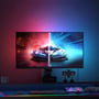 Gaming setup med en 27" skærm, der viser et bilspil med delt skærm og en RGBIC LED strip langs kanten, oplyst med røde og blå nuancer.