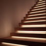 V-TAC COB LED strip installeret diskret under trin på en moderne trappe i træ, der skaber en elegant effekt.
