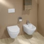 Hvidt Villeroy & Boch ViConnect E200-vægtryk på væggen over toilet og bidet i et badeværelse.